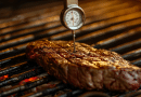 how to use a meat thermometer - photo of a meat thermometer in a piece of steak on a bbq grill